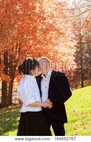 Autumn couple walking park and kissing. Autumnr friends walk outdoor. First date and tender and passionate kiss two young people in good weather day. Lights of sun on background. Good mood and happy