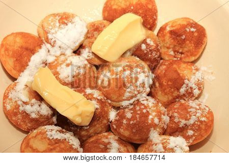 Poffertjes Dutch small fluffy pancakes served with powdered sugar and butter.