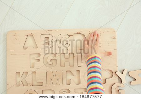 Hand of cute little child playing with letters at home