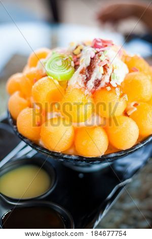 bingsu is a Korean shaved ice dessert with sweet toppings such as chopped fruit, condensed milk, fruit syrup, and red beans.