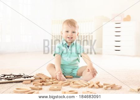 Cute little child playing with letters at home