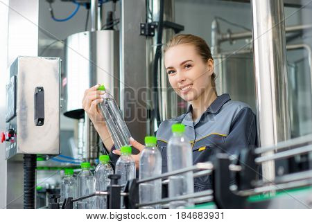 Female worker at a water bottling factory near conveyor