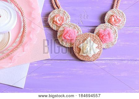Beautiful women's necklace. Women's necklace made of ribbons, cords and felt. Materials to create jewelry on a wooden table. Floral summer accessory. Top view