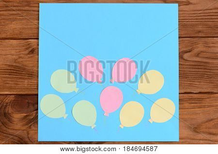 Making a card with paper air balloons. Step. Lesson for children. Card with paper air balloons isolated on a wooden table. Preschool and kindergarten crafts activities. Closeup. Top view
