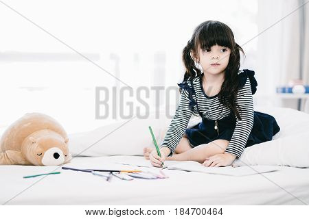 Portrait of beautiful kid having activity on her bed.