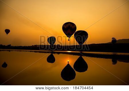 Silhouette and reflecion of hot air balloon going up in the sky when sunset.