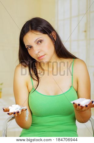 Young beautiful woman with a green blouse holding a couple of hygenic towels in both hands.