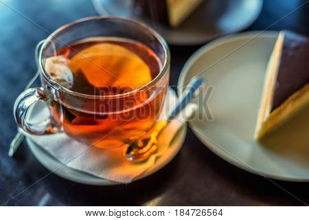 Close-up of morning cup of tea with cake inside cafe