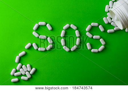 White Pills On Green Background, Which Forming The Word - Sos, With A Blister Of Pills On Background
