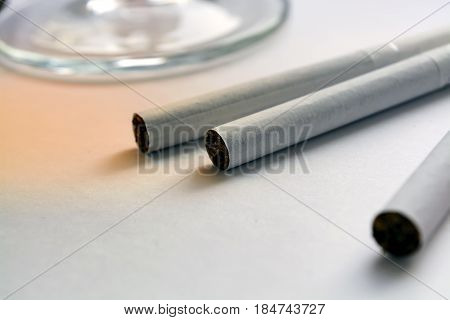 Glass of brandy cognac and cigarette on an white table. Close-up view