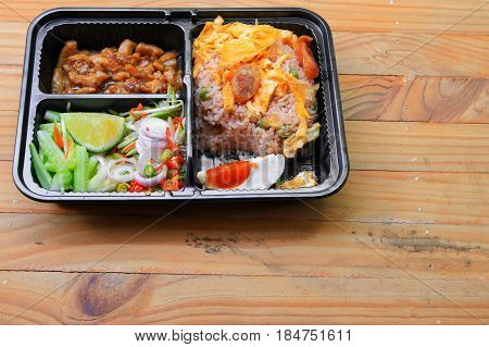 fried rice with shrimp paste include mango egg pork onion vegetable in box black / Thai style food on a wood table background