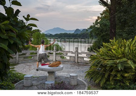 Guilin China - July 31 2012: Man practicing Tai chi in the banks of the Li River in Guilin China.