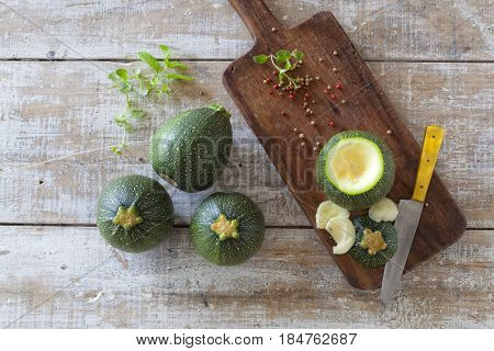 Round zucchini on a wooden table and cutting board.