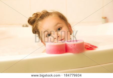 little beautiful girl behind of a pink bathsponge.