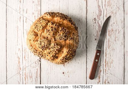 Fresh Seedy Bread With Knife On A White Wooden