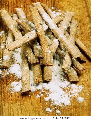 Stack of Freshly Baked Whole Wheat Bread Sticks with Dough closeup on Wooden Cutting Board