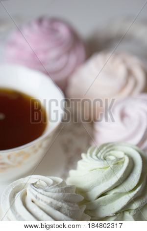 Sweet homemade dessert - marshmallow (zephyr) with cup of tea.Homemade marshmallows on a light background. Russian currant and mango zephyr.