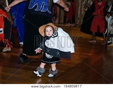 Metlakatla, Alaska - July 26, 2008; Cute child North American Indian child in traditional costume performs with group indigenous locals for group of tourists at small village on Inside Passage Metlakatla Alaska.
