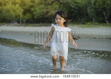 children walking on the beach at the sun shining beach in Thailand.