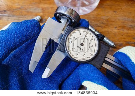 Measurement of the ball bearing inner diameter by a master in gloves with a slide caliper