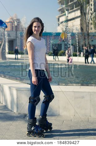 Beautiful and happy Roller Girl skating in the park. She looks happy and smiles.