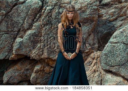 young beautiful woman with tarot cards in her hands with stone background