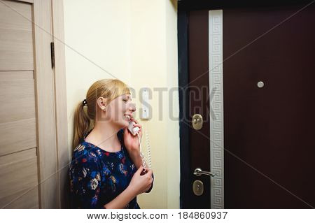 Blonde Woman Answers The Intercom Call, Hold The Phone To His Ear, Waiting For The Arrival Of The Lo