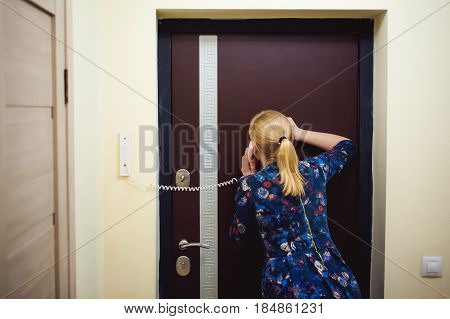 Blonde Woman Answers The Intercom Call, Hold The Phone To His Ear, Waiting For The Arrival Of The Lo