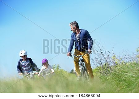Father with kids riding bicycle in countyside