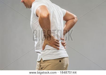 people, healthcare and problem concept - close up of man suffering from pain in back or reins over gray background
