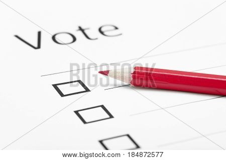 Voting bulletin with red pencil. Close-up photo with shallow depth of field