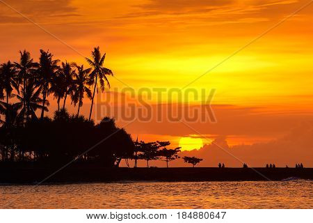 Tourists relaxing on beach and enjoying view of sunset in sea. Traveling freedom and active lifestyle concept.