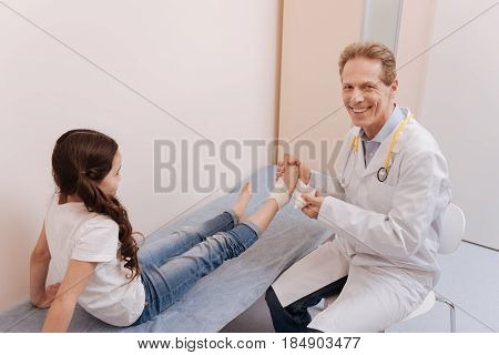 Professional materials. Qualified attentive capable rheumatologist applying various method for treating his little patient and fixating her joints in the right position