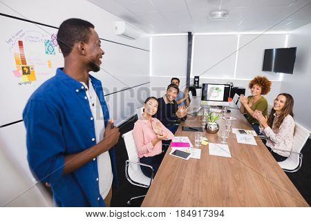 Colleagues clapping after presentation in confrence room at creative office