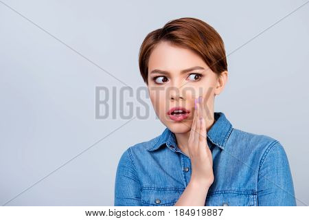 Young Beautiful Red Hair Girl Is Telling Someone A Secret And Looks Shocked. She Is Dressed In Jeans