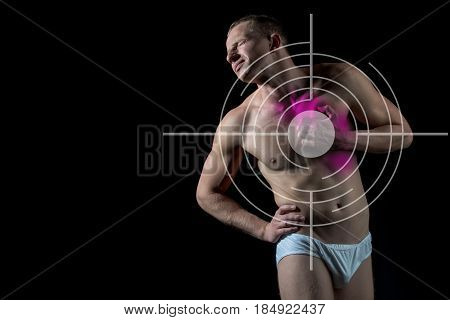 man with target on chest has heartache standing over black background A guy with bare body and muscular torso in white pants. Concept with Healthcare And Medicine copy space