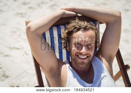 High angle portrait of young woman relaxaing on lounge chair at beach during sunny day