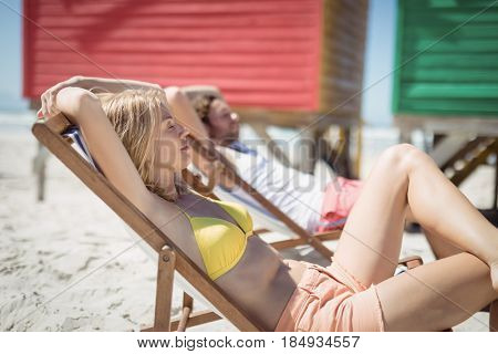 Young woman relaxaing on lounge chair at beach during sunny day