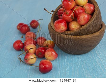 Background of ripe cherries. Pile of fresh and tasty cherries in wooden bowl. Fresh cherries scattered on a wooden table.