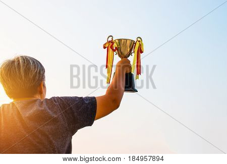 winner and champion concept Sport Woman Hand holding championship trophy against in blue sky