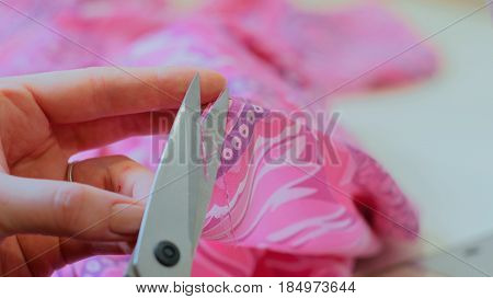 Professional dressmaker, tailor cutting a piece of cloth in her workshop. Fashion and tailoring concept