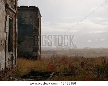 ruins of abandoned building in tundra with coalmine in the background