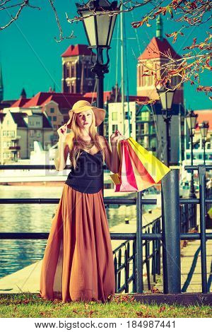 Spending money on sales buying things concept. Fashionable woman relaxing and standing with shopping bags in town wearing glamorous outfit and big sun hat