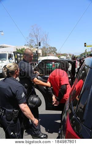 LOS ANGELES California- May 1, 2017: A person in a Black Ski Mask is arrested and put in a police car at a Protest Rally Against President Donald J.Trump on May 1, 2017 in Los Angeles, California
