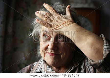 Elderly woman stress and headache on a dark background