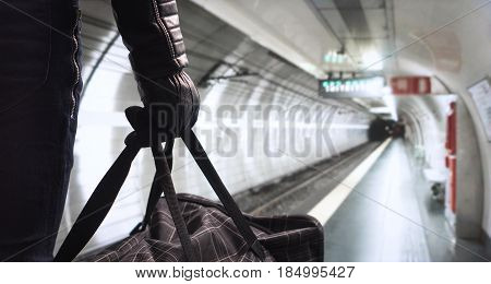 Terrorism in subway concept. Dangerous criminal with black bomb bag standing in underground station planning attack. Threatening man in the shadow with an evil plan . Terrorist in metro platform.