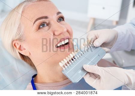 Dentist Selecting Patient's Teeth Color With Palette In Clinic
