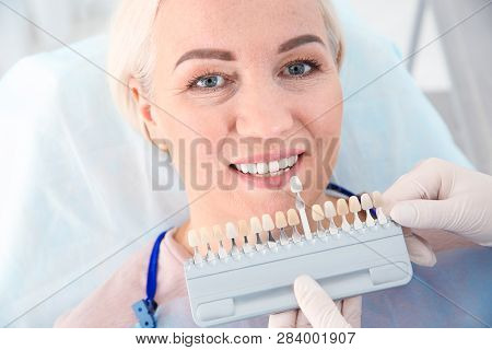 Dentist Selecting Patient's Teeth Color With Palette In Clinic