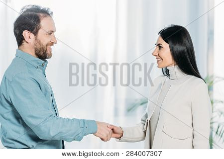 Side View Of Psychotherapist And Patient Shaking Hands And Smiling Each Other