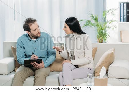 Bearded Psychotherapist And Young Female Patient Talking And Looking At Each Other